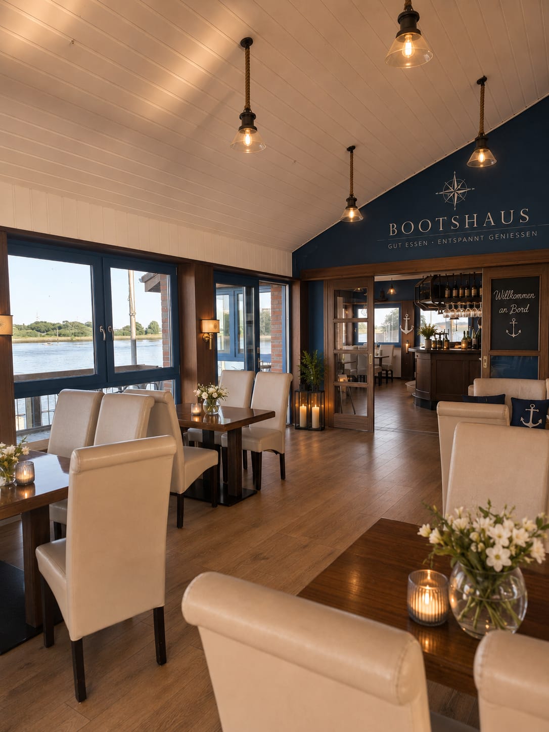 Innenraum des Bootshaus mit Eichentischen und Blick aufs Wasser